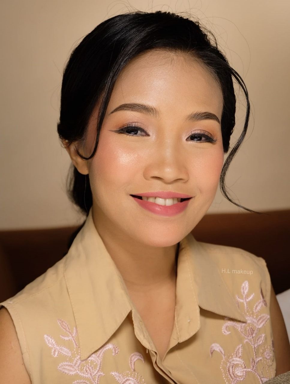 A woman in a tan shirt is smiling for the camera.