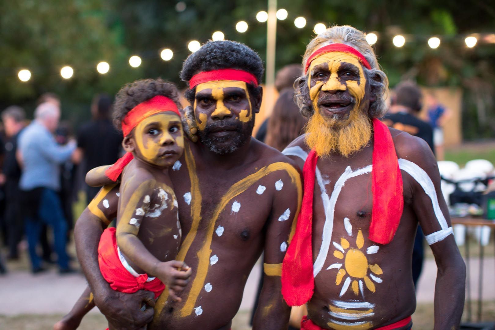 Two men and a child are standing next to each other with their faces painted.