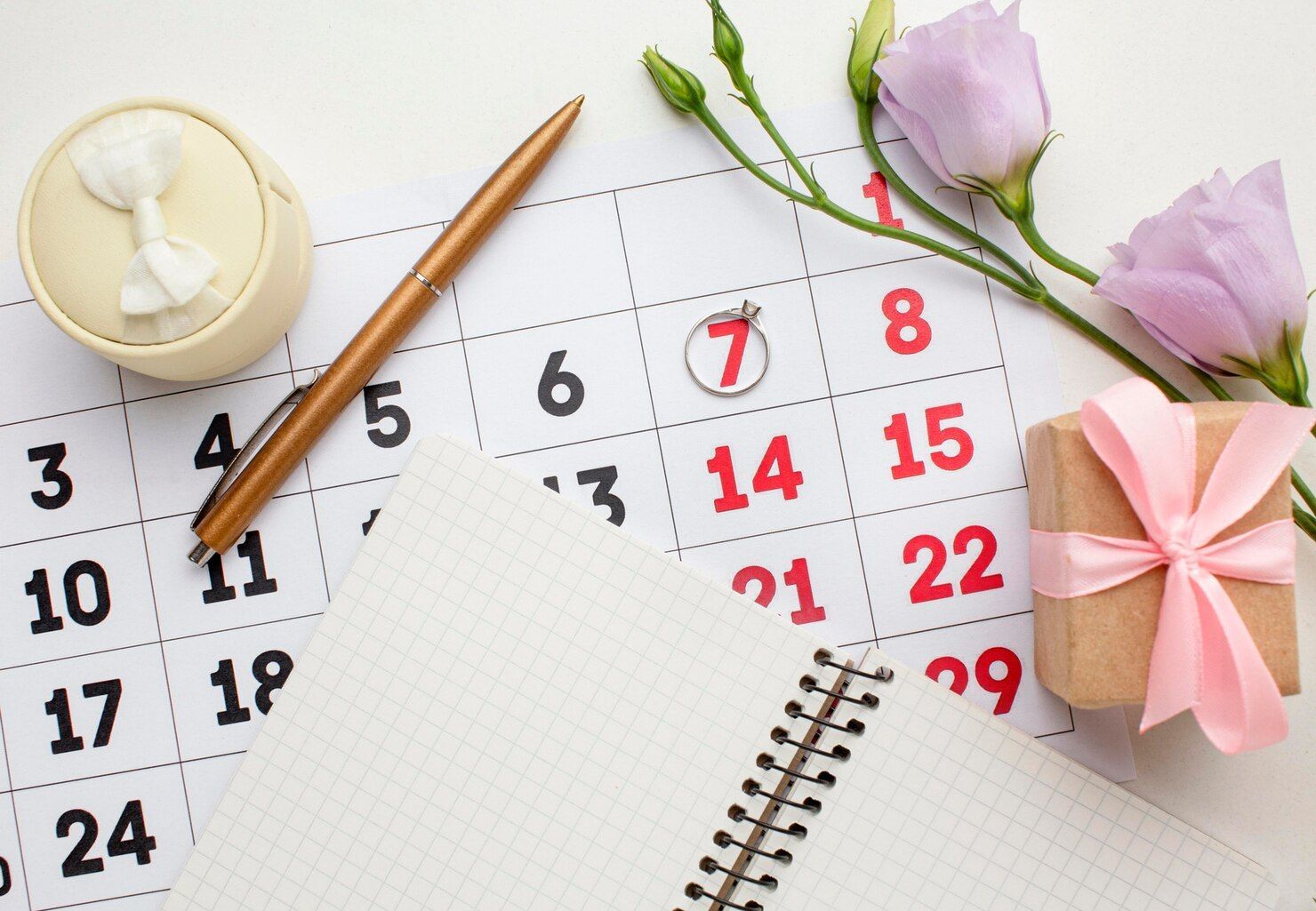 A calendar with a pen , flowers and a gift on it