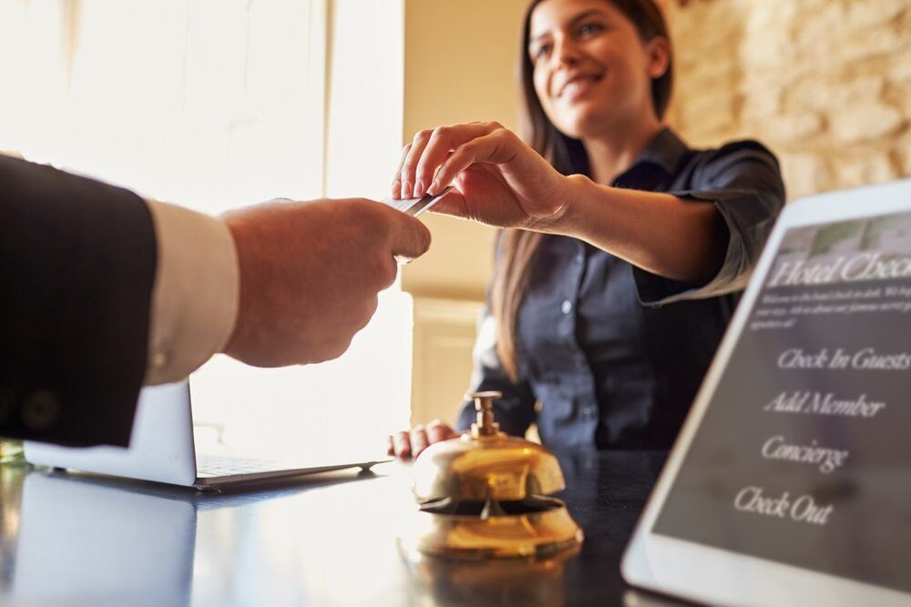 A Woman is Giving a Credit Card to a Man at a Hotel Counter — Zen Luxury Retreats in Darwin City, NT