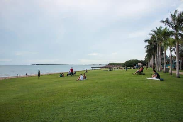 A Group of People Are Sitting on The Grass Near the Beach — Zen Luxury Retreats in Darwin City, NT