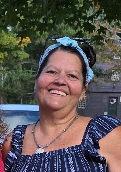 Three people at a white table reviewing documents. One points at a paper, laptop, coffee, and juice visible.