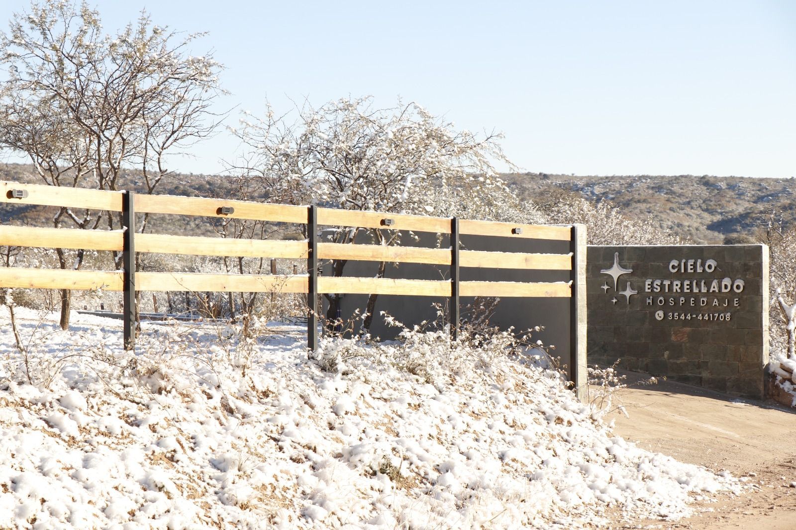 Valla rural nevada con un cartel de piedra que dice
