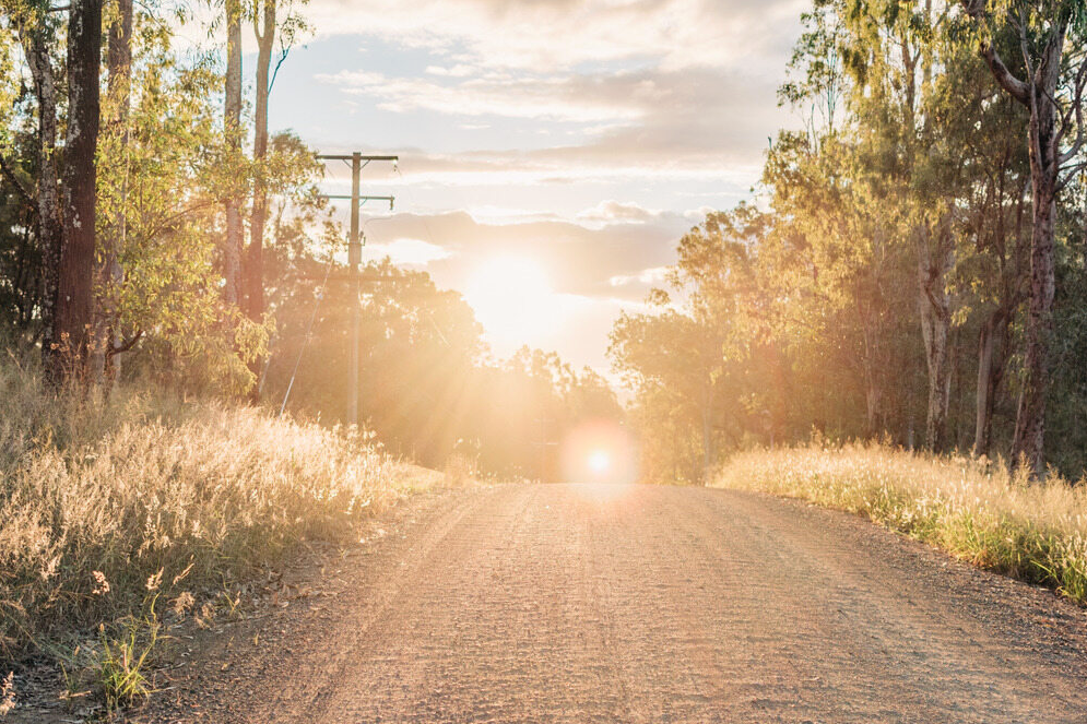A Rural Stone Road With Trees and the SunSetting Between Them — Serenity Strides in Logan, QLD