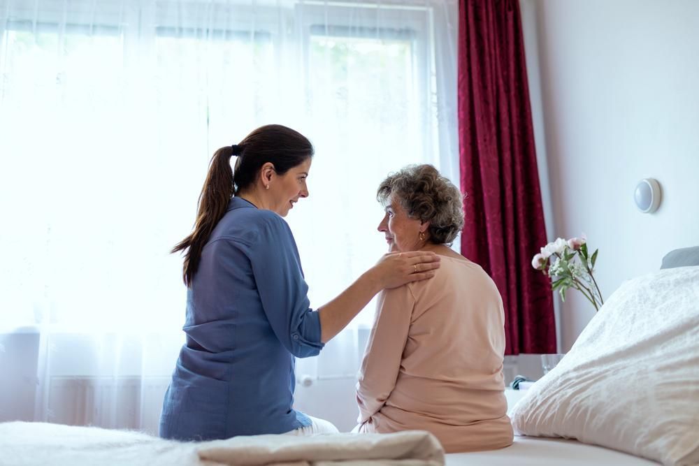 Nurse is Talking to an Elderly Woman Sitting on a Bed — Serenity Strides in Redbank Plains, QLD