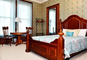 A bedroom with a bed, table, chairs and a lamp.