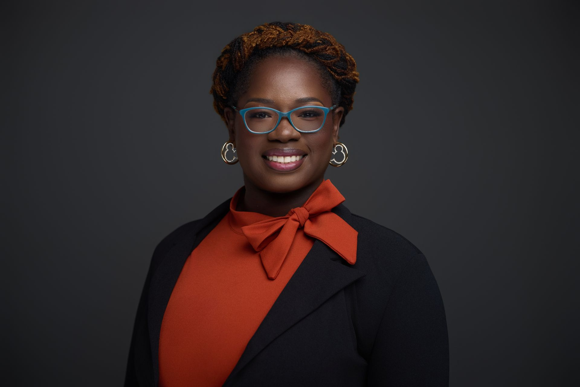 Guidance, honest communication, and client-first service Woman with glasses and a red bow tie, smiling, wearing a black blazer.