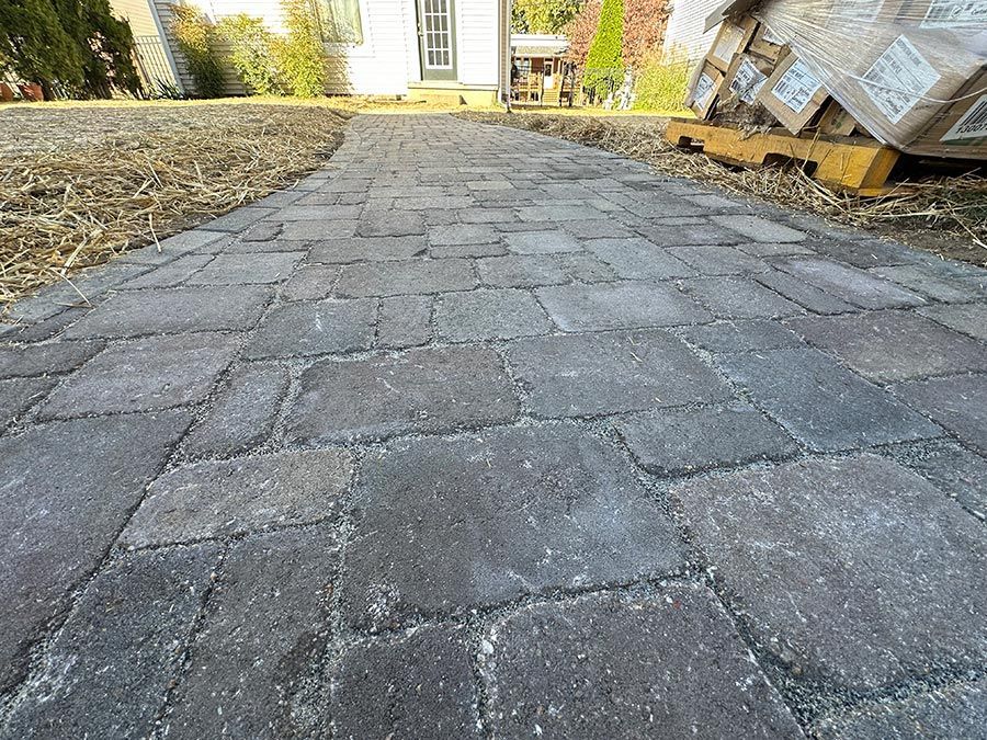 Stone paver walkway leading to a house entrance, with mulch beds on both sides.