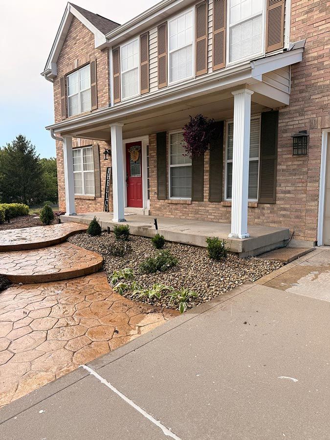 Two-story brick house with a red front door, covered porch, and landscaped walkway beside a driveway