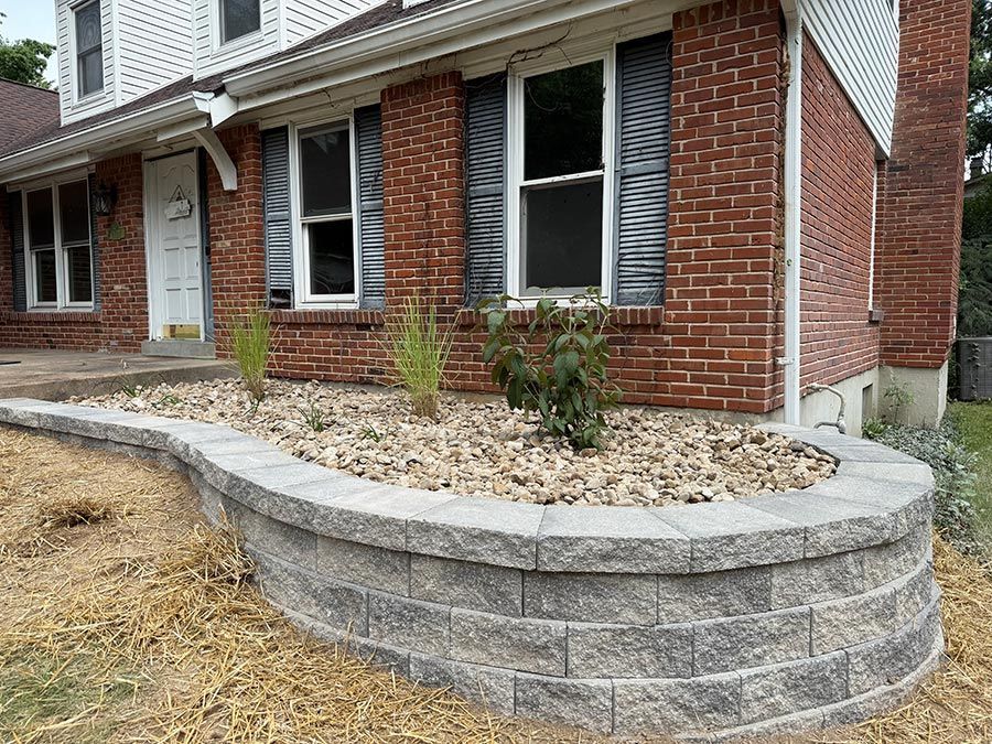 Brick house front with raised stone retaining wall and mulched planting bed