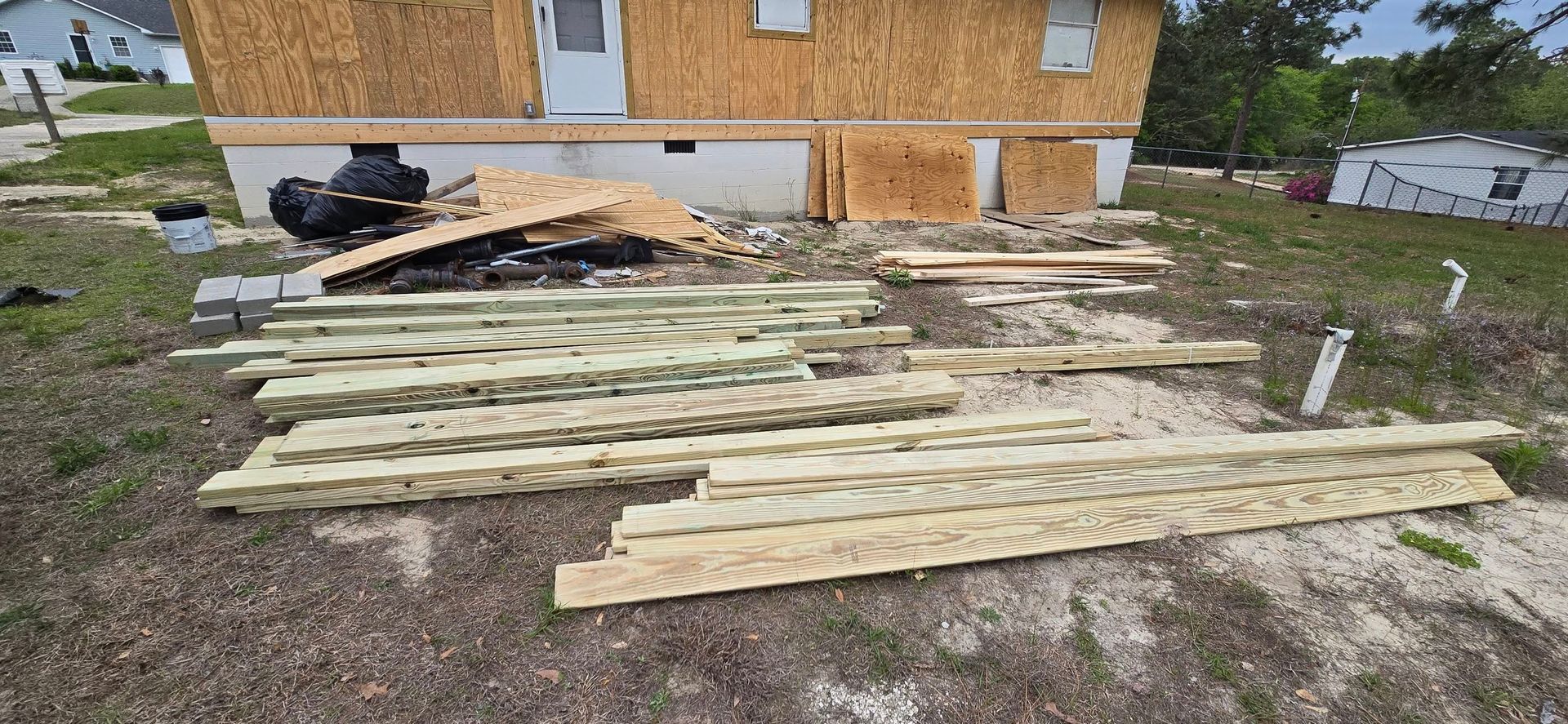 Construction site with wooden planks, plywood, and a house under construction.