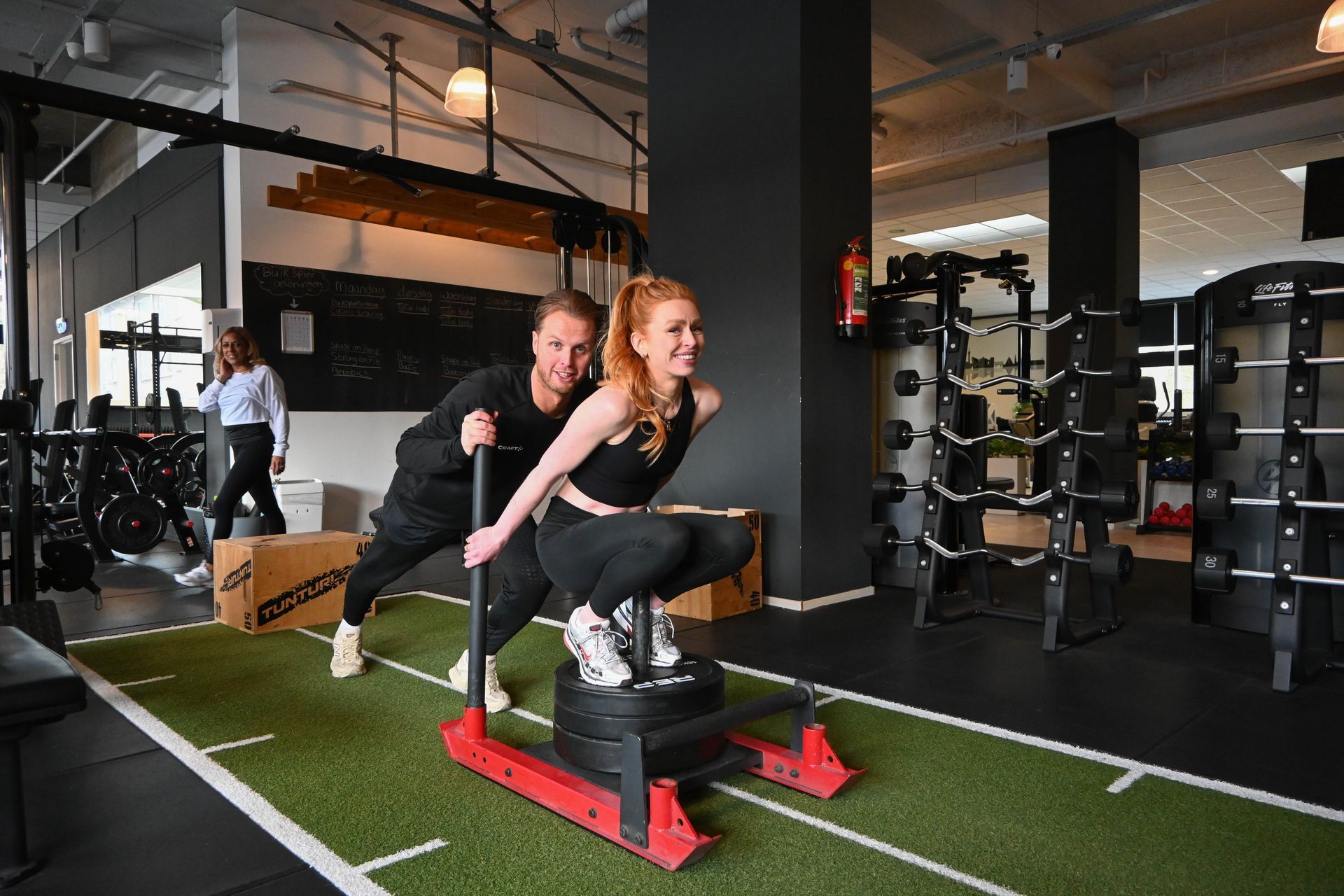 Een man tilt halters op een bankje in een sportschool.