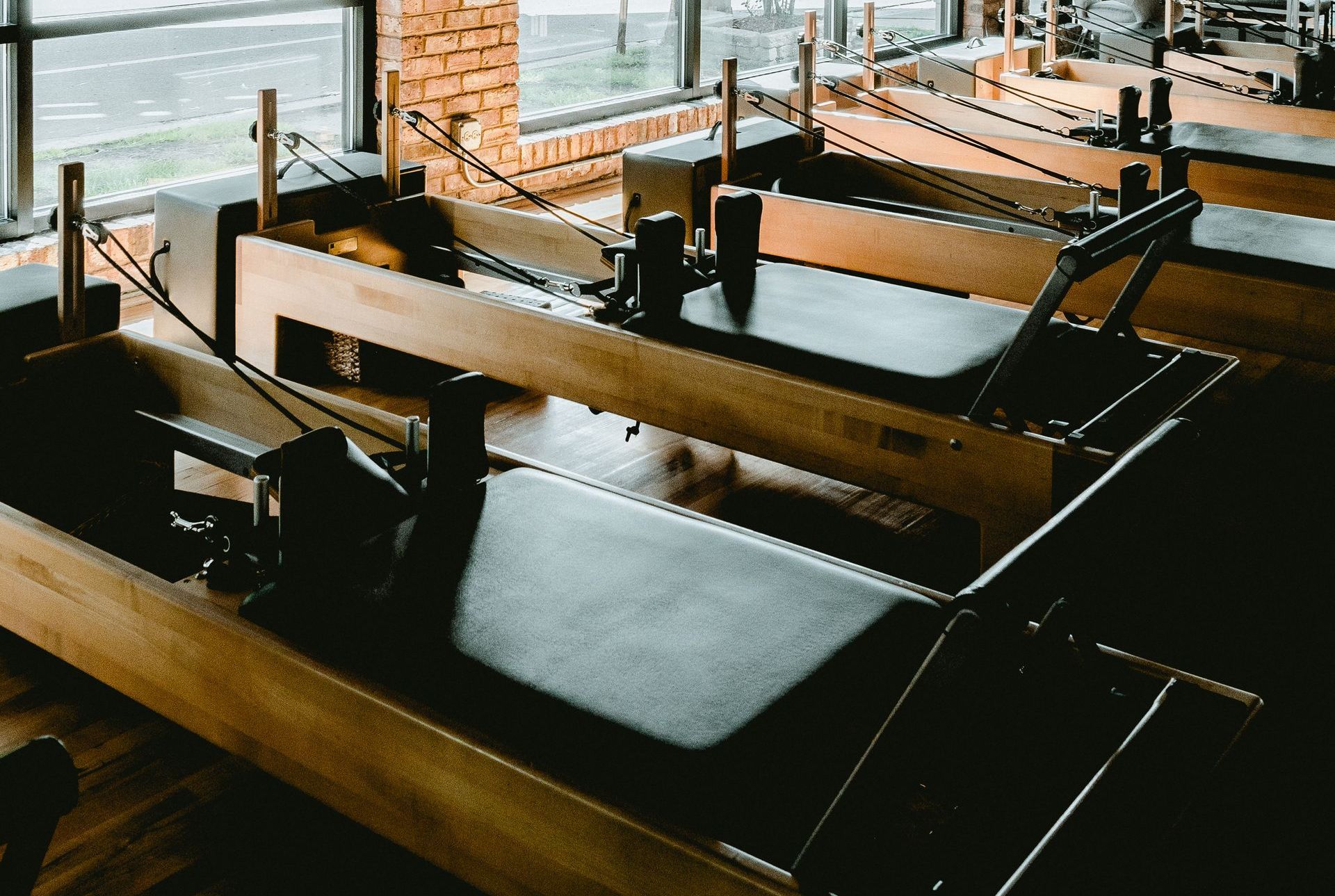 A row of pilates machines are lined up in a gym.