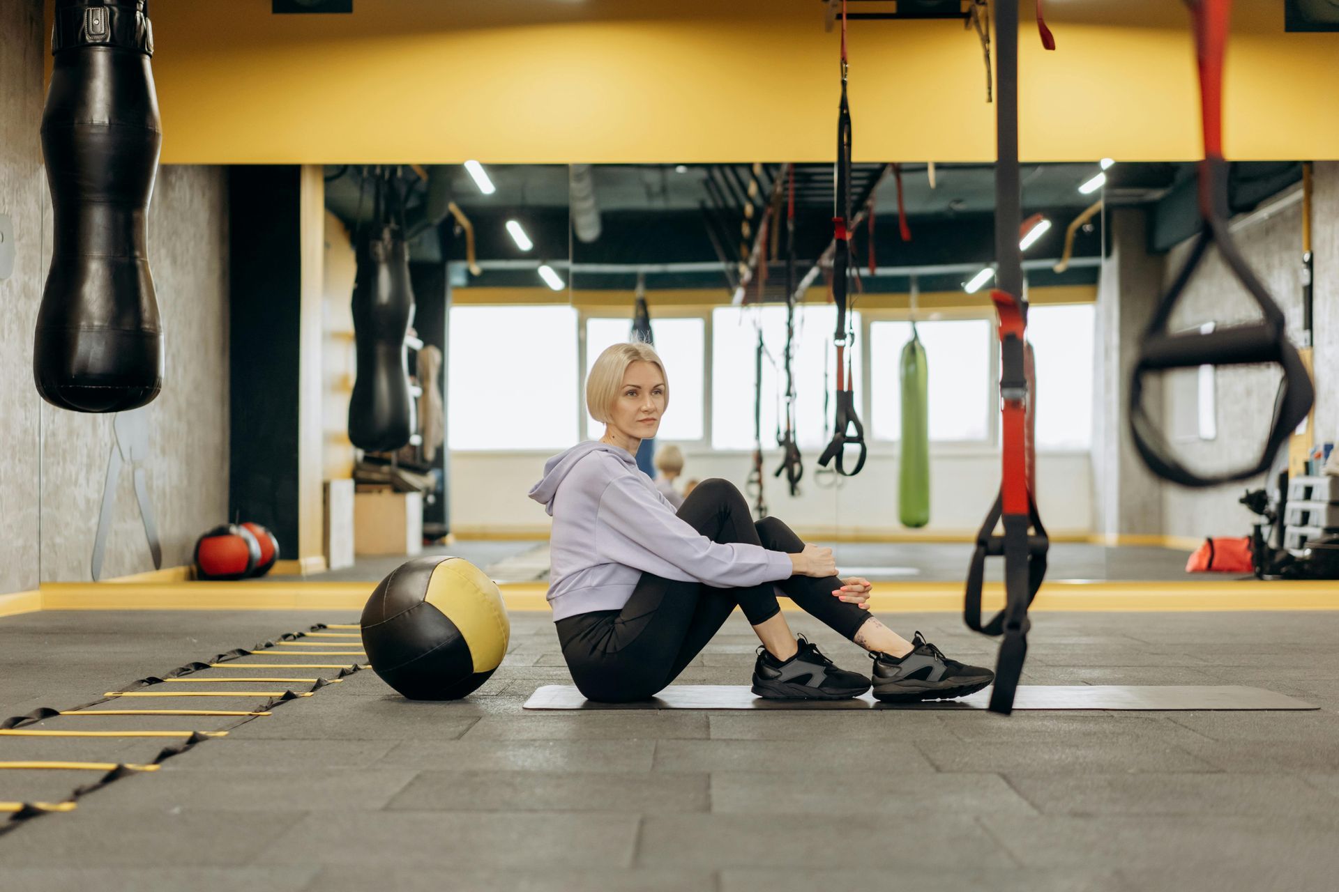 A woman is sitting on the floor in a gym.