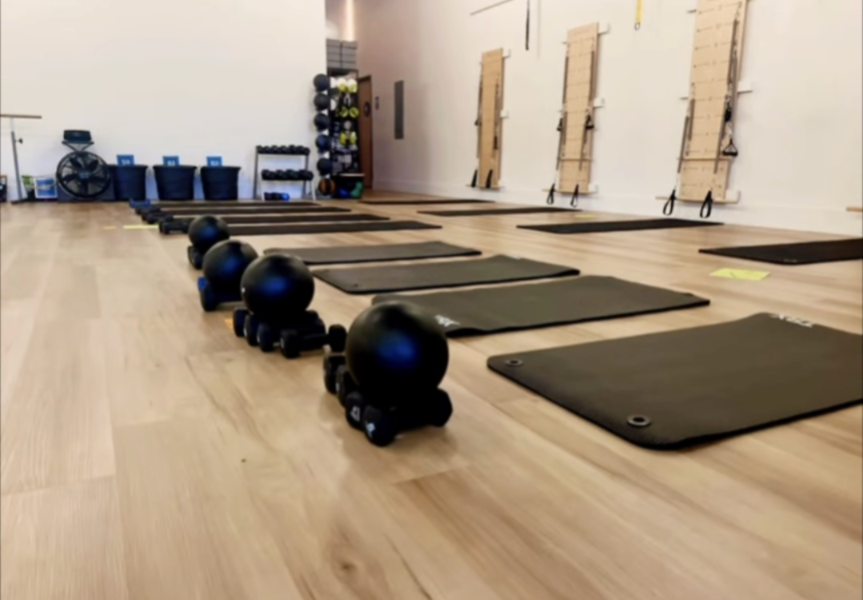 A gym with a lot of mats and balls on the floor