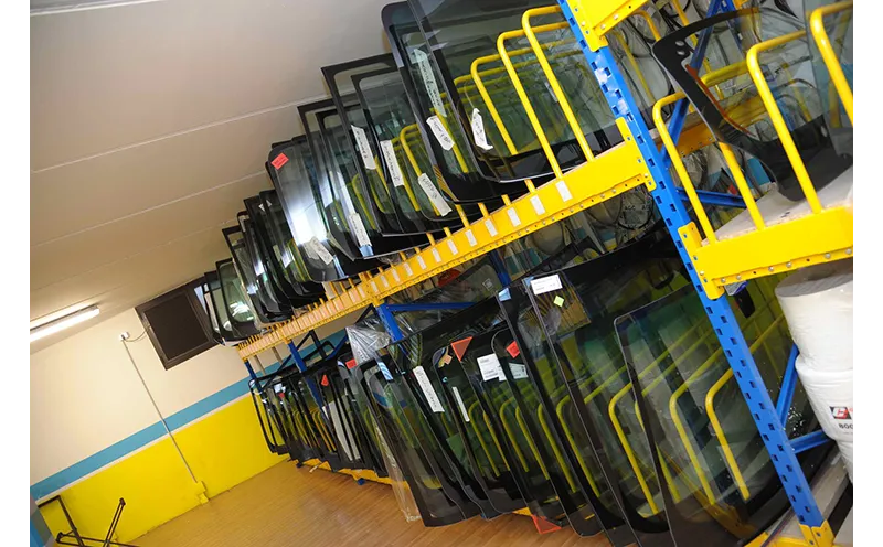 Corridoio di magazzino con portiere e pannelli della carrozzeria impilati su scaffalature metalliche gialle