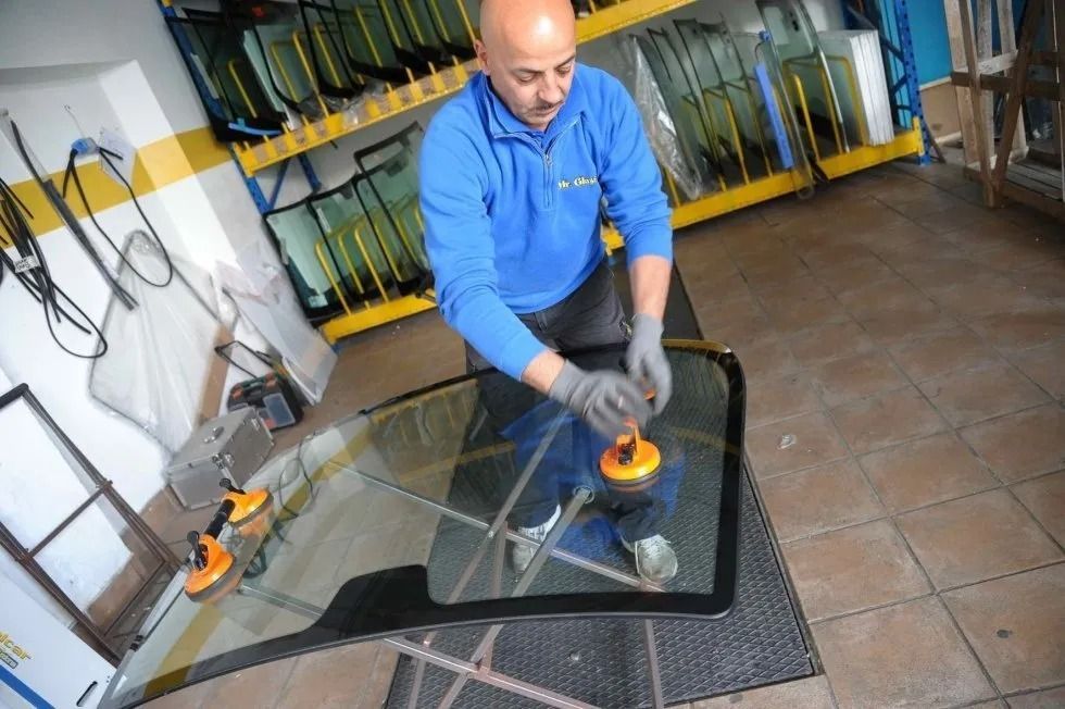 Un operaio lucida una lastra di vetro con una lucidatrice elettrica in un'officina.