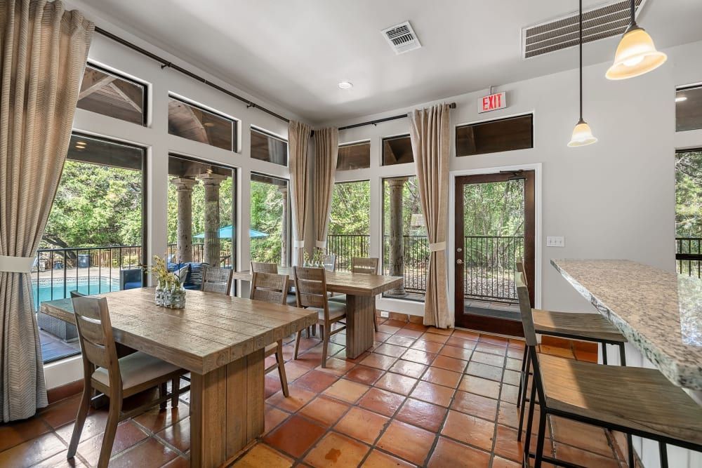A dining room with a table and chairs and a large window at Marquis at Caprock Canyon in Austin, TX.