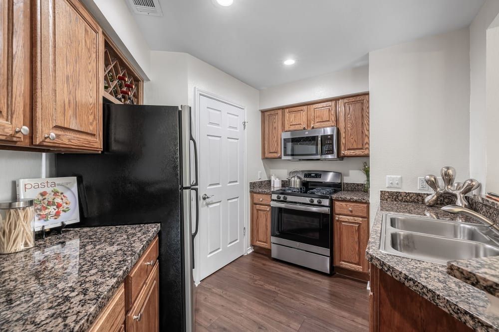 A kitchen with a black refrigerator, stove, microwave, and sink at Marquis at Caprock Canyon in Austin, TX.