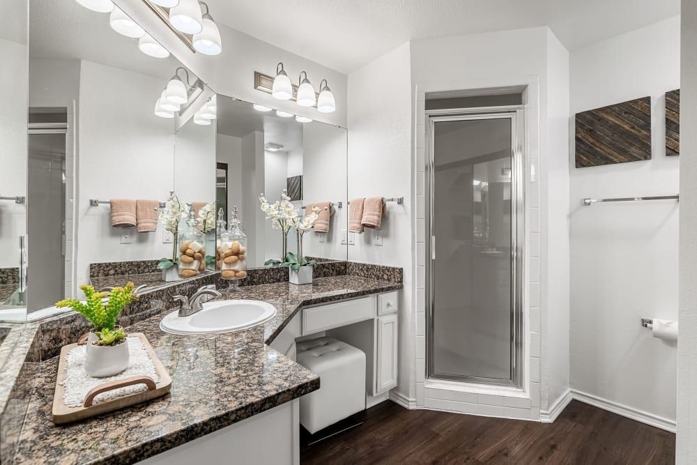 A bathroom with a sink, mirror, and walk-in shower at Marquis at Caprock Canyon in Austin, TX.