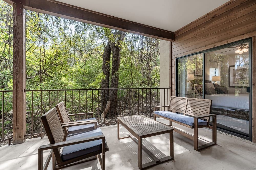A balcony with a couch, chairs, and a coffee table at Marquis at Caprock Canyon in Austin, TX.
