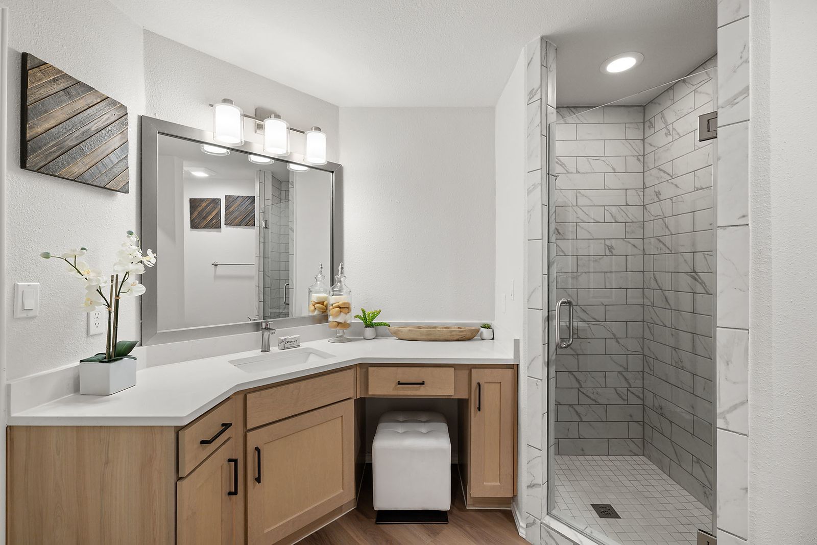 Modern bathroom with wood vanity, large mirror, white countertop, and tiled walk-in shower at Marquis at Caprock Canyon in Austin, TX.