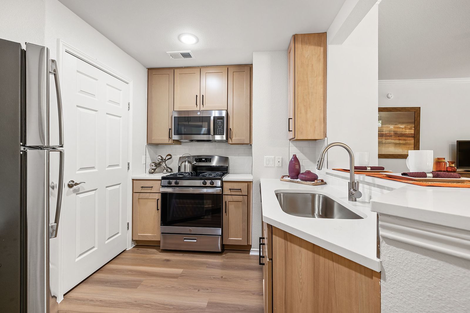 Compact modern kitchen with stainless steel appliances, wood cabinets, and a white countertop at Marquis at Caprock Canyon in Austin, TX.