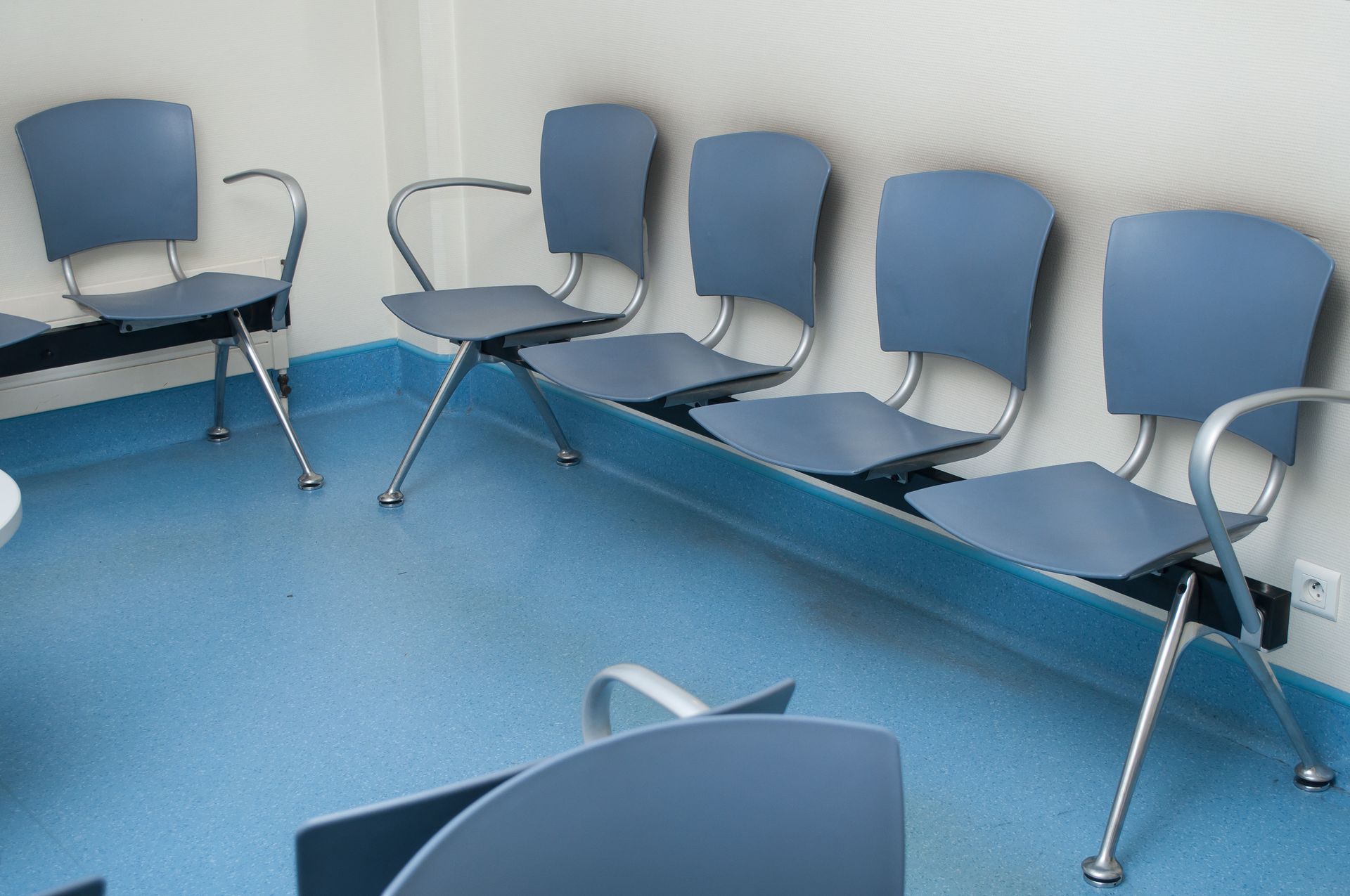 Des chaises bleues dans une salle d'attente avec un sol bleu et des murs blancs.
