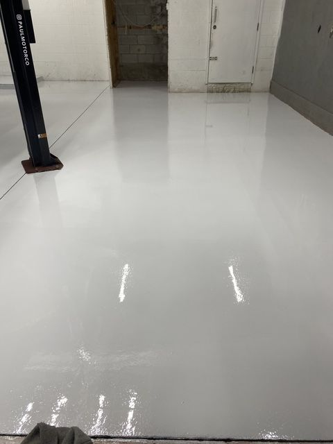 Sol en époxy blanc dans un garage avec ascenseur et porte.