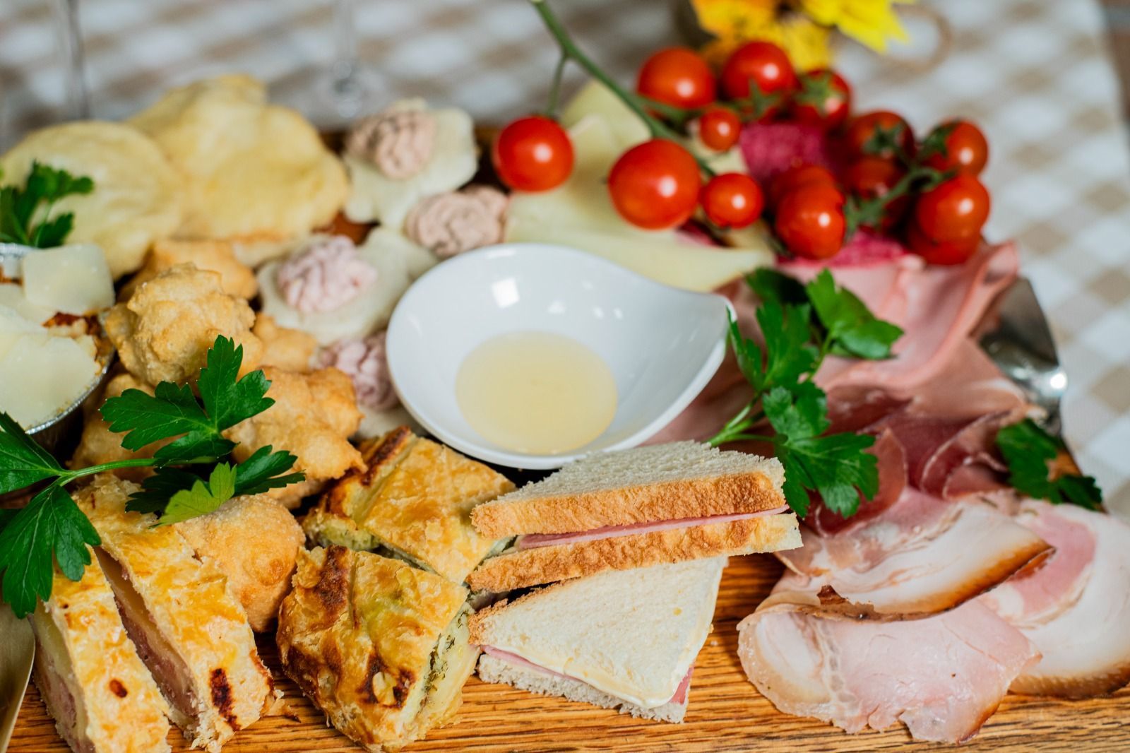Formaggi assortiti, pane, salumi e pomodorini disposti su un tavolo rustico con una piccola ciotola d'olio