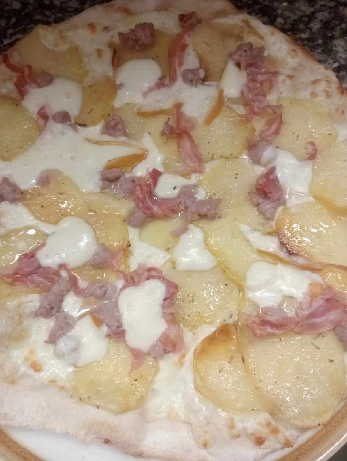 Primo piano di una pizza condita con ananas, prosciutto e formaggio fuso.