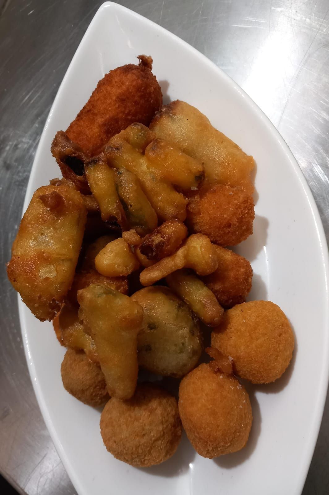 Assortimento di snack fritti su un piatto bianco, con bocconcini e panini dorati.