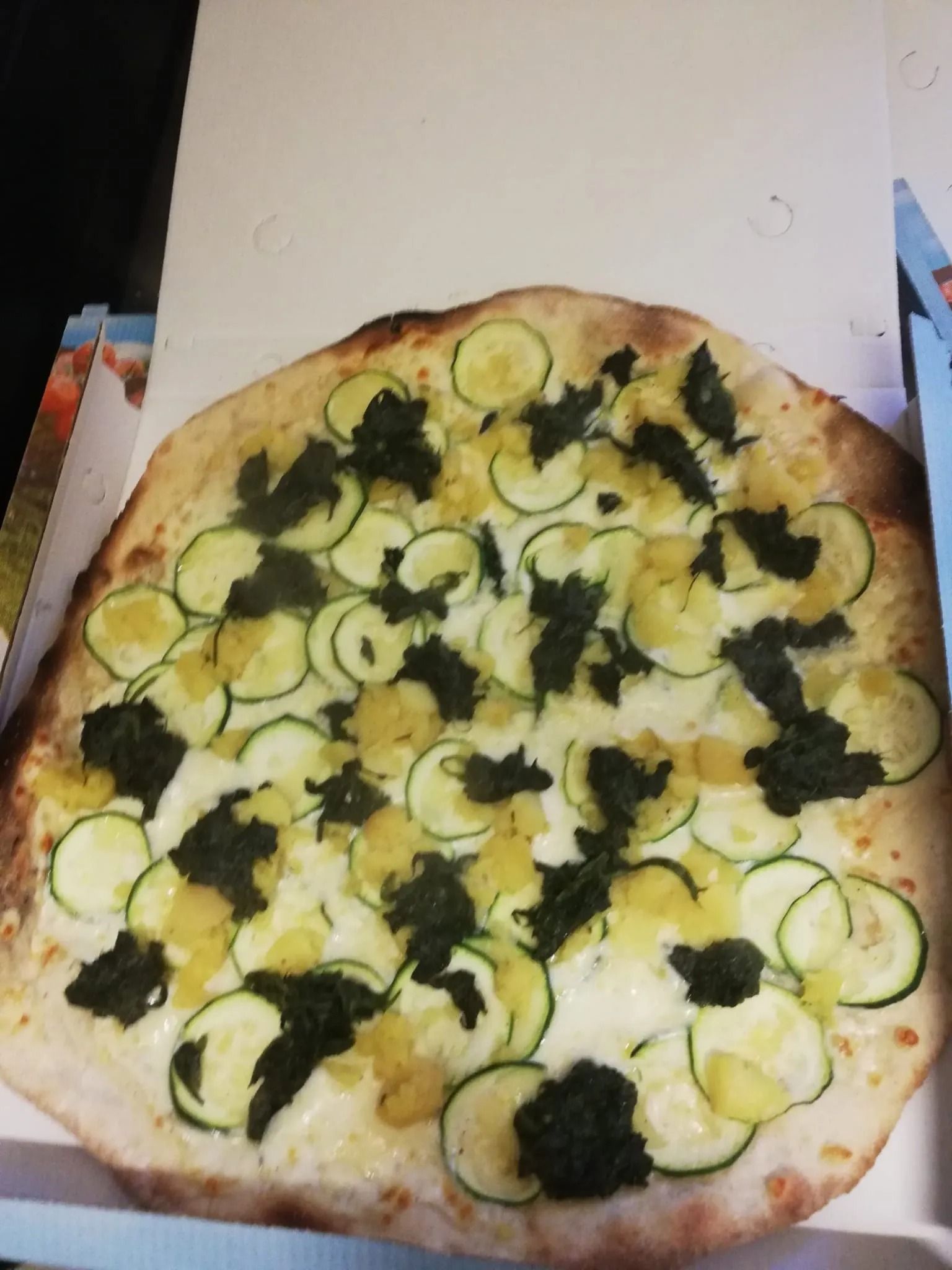 Pizza rotonda alle verdure con fette di zucchine e verdure miste su un piatto