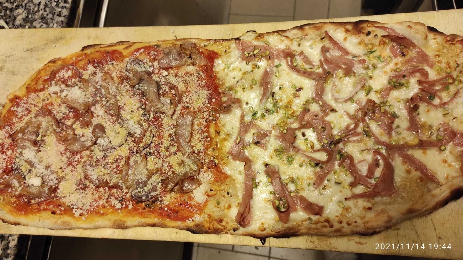 Pizza rettangolare con due ingredienti, metà formaggio e metà carne al sugo, su un vassoio