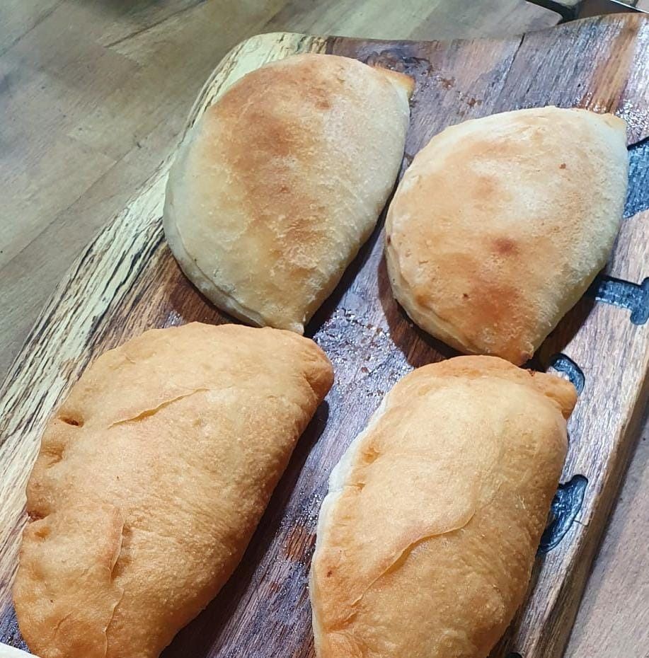 Quattro pasticcini dorati al forno su un tagliere di legno.