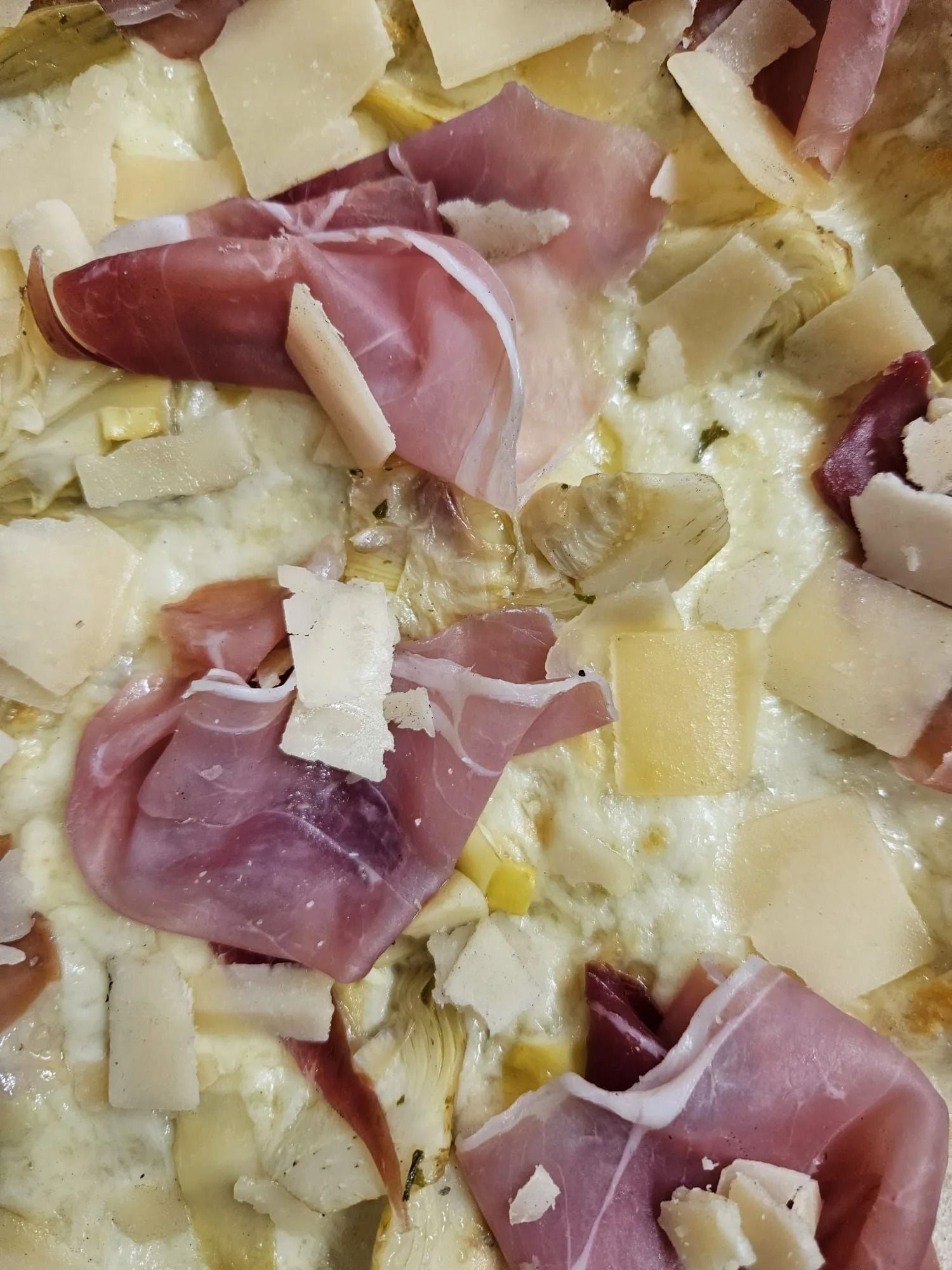 Pizza condita con prosciutto crudo, formaggio grattugiato e salsa cremosa