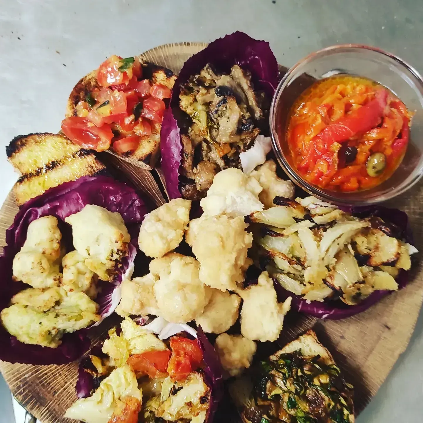 Verdure grigliate assortite e salse servite su un piatto con pane pita.