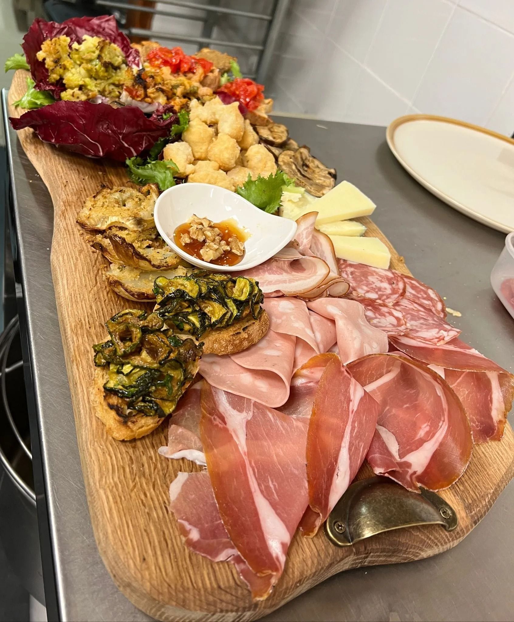 Tagliere di salumi con affettati, formaggi, creme spalmabili, frutta secca e verdure arrostite su un tavolo