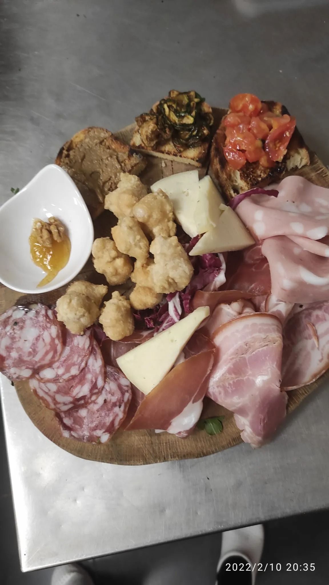 Tagliere di salumi con affettati, formaggi, uva, cracker e una ciotolina di senape.