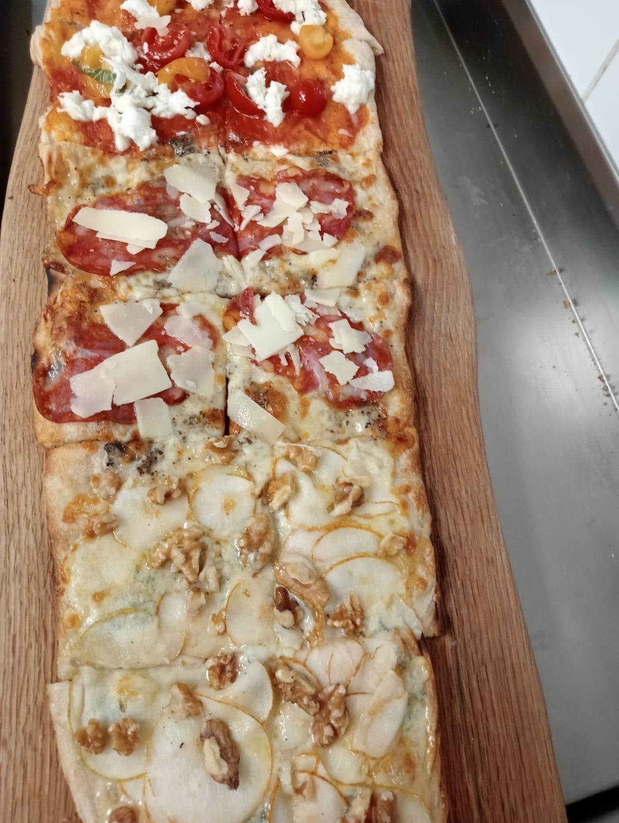 Vassoio rettangolare per pizza con fette assortite, tra cui fette con pomodoro rosso e fette con formaggio bianco.