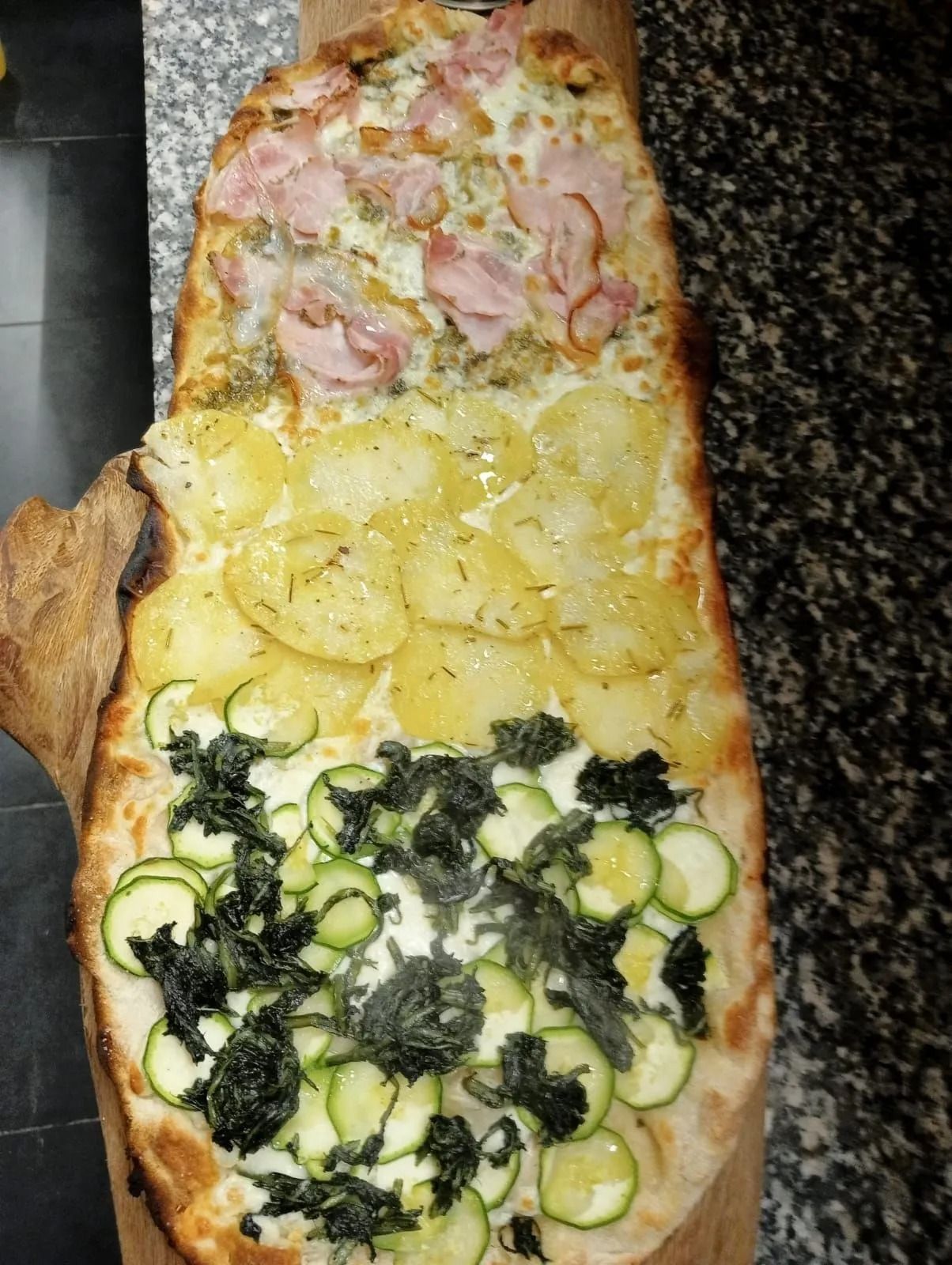 Una lunga focaccia farcita con tre strati di ripieno: prosciutto, patate a fette e zucchine alle erbe aromatiche.