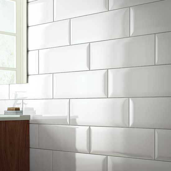 A bathroom with white tiles on the wall and a window.