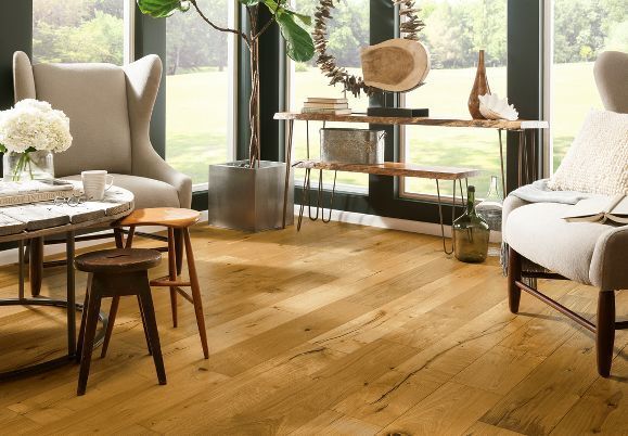 A living room with hardwood floors , chairs , a table and a large window.