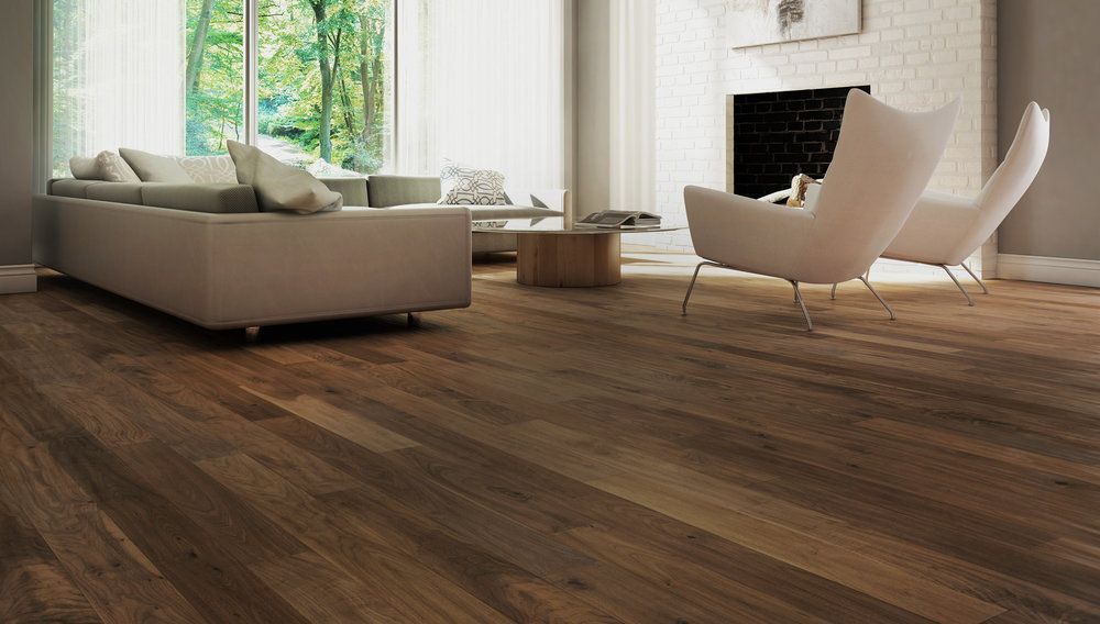 A living room with hardwood floors , a couch , chairs and a fireplace.