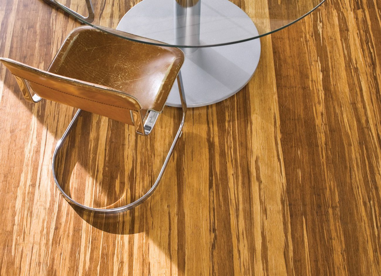 A chair sits next to a glass table on a wooden floor