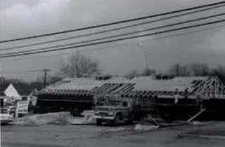 Collapsed roof over a truck in a snowy roadside scene with power lines overhead