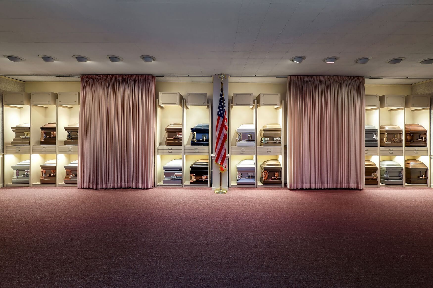 Wide hotel lobby with purple carpet, beige curtains, and illuminated display shelves.