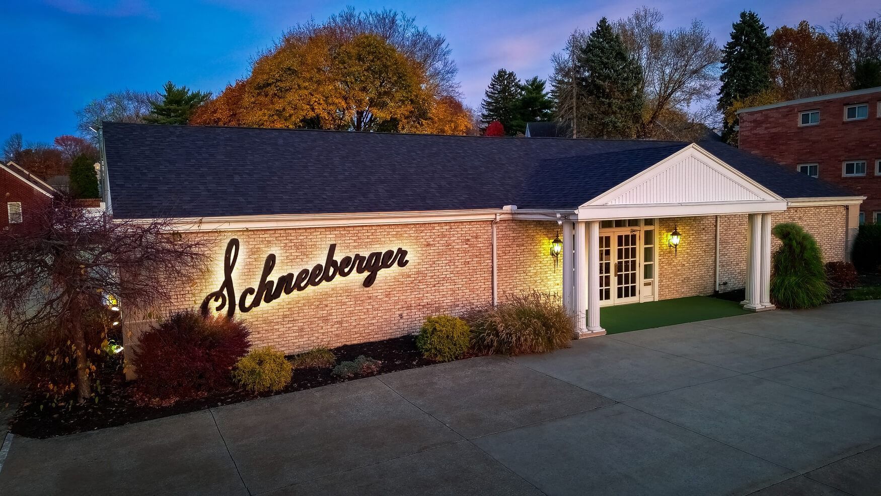 Schreiberger storefront at dusk, with lit entrance and ivy-covered brick wall