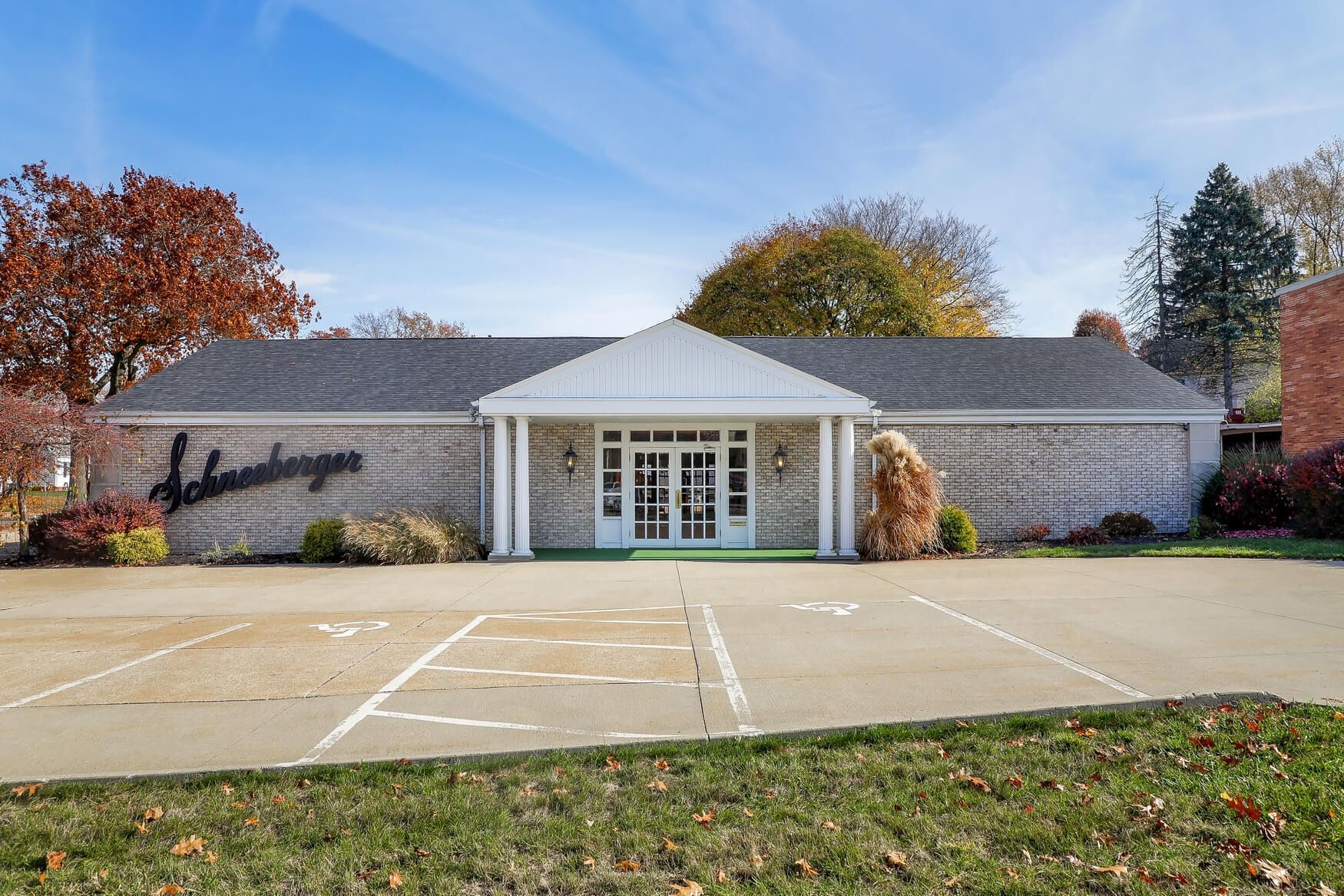 Single-story brick building with white entrance and empty parking lot in front