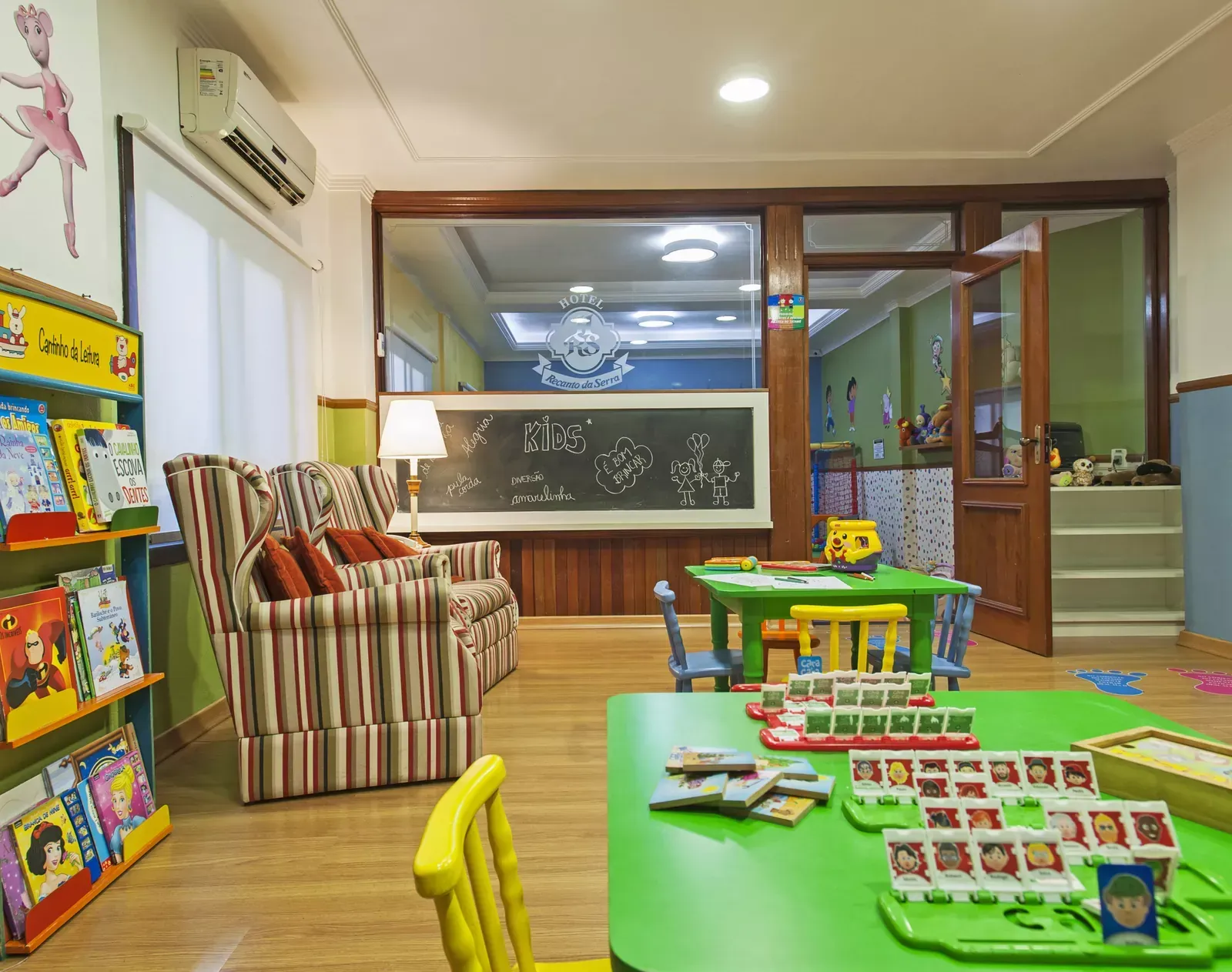 Sala de jogos infantil iluminada com brinquedos coloridos, livros e uma poltrona listrada sob luz aconchegante.